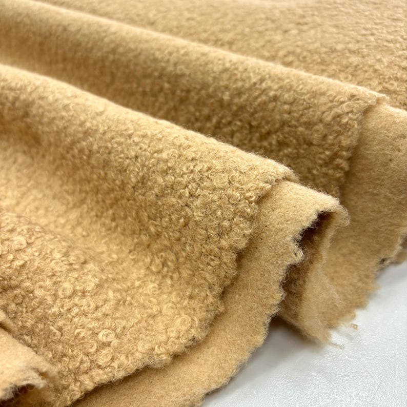 May include: Close-up of a soft, brown, fuzzy fabric with a textured surface. The fabric is folded in a way that shows the texture and the soft, fluffy feel.