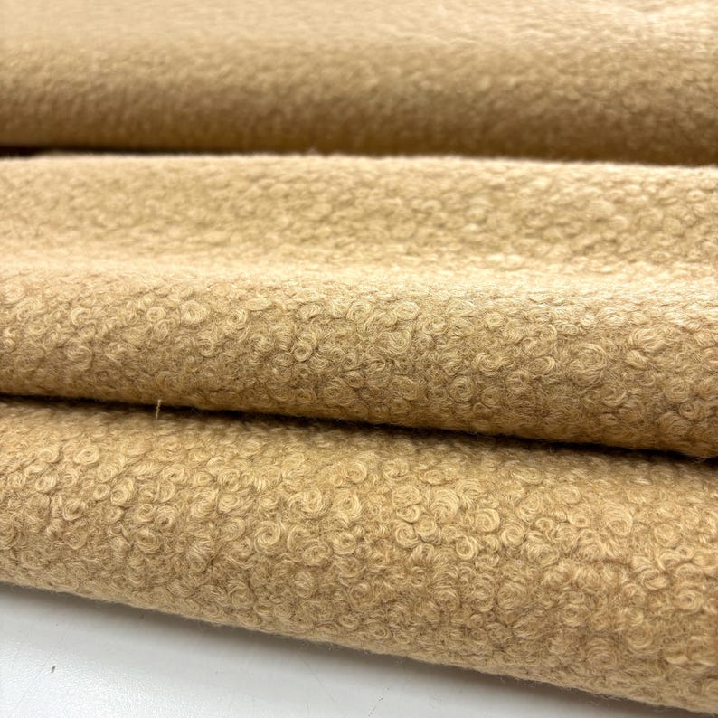 May include: Close-up of a soft, brown, fuzzy fabric with a textured, swirl pattern.