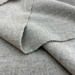 May include: Close-up of a gray fabric with a textured surface. The fabric is folded in half, showing the inside and outside of the material.