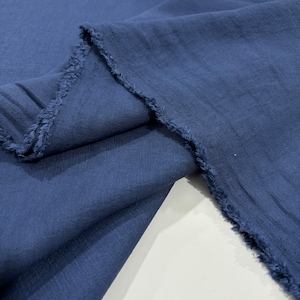 Puede incluir: Primer plano de una tela azul oscuro con un borde sin rematar. La tela es suave y tiene una superficie ligeramente texturizada.