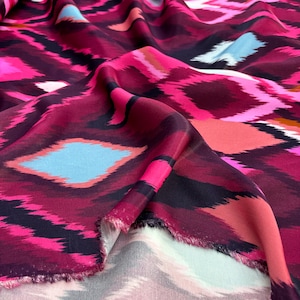 May include: Pink, black and blue patterned fabric with an abstract design. The fabric is soft and silky.