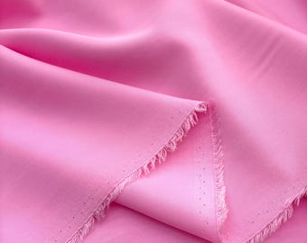 Puede incluir: Primer plano de un trozo de tela rosa doblada. La tela tiene una textura suave y brillante y un borde deshilachado. El color es un rosa vibrante y liso, y la tela parece ligera.