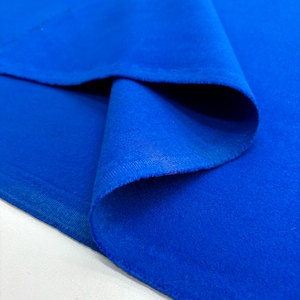 Puede incluir: Un primer plano de una tela azul brillante con una textura suave y aterciopelada. La tela está doblada por la mitad, mostrando la superficie lisa y la textura sutil del material.