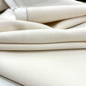 May include: Close-up of a folded piece of off-white fabric with a soft, textured surface.