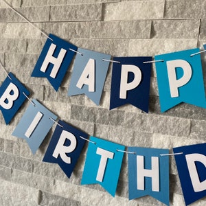 May include: Blue and white paper banner with the words "Happy Birthday" in white letters.