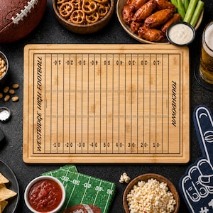 May include: A rectangular bamboo cutting board featuring a laser-engraved American football field design. The board includes yard line markings, the text "WESTRIDGE HIGH FOOTBALL" on the left side, and the word "TOUCHDOWN" on the right side.