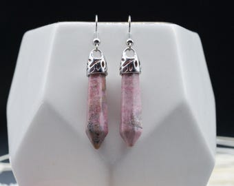 May include: A pair of silver dangle earrings with pink and white gemstone pendants. The pendants are shaped like long, pointed crystals.