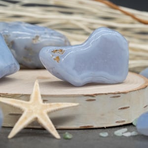 May include: A collection of five blue agate stones, some with white and gold inclusions, arranged on a wooden surface with a starfish.