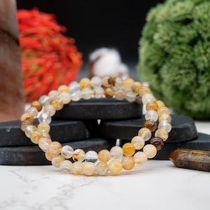 May include: A multi-strand bracelet made of clear, yellow, and brown gemstone beads. The bracelet is made of natural stones and is a beautiful and unique piece of jewelry.