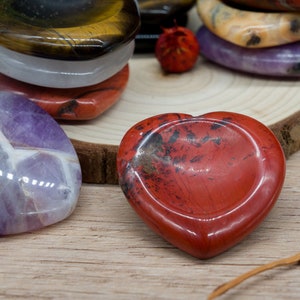 Puede incluir: Surtido de piedras pulidas en forma de corazón de varios colores, incluyendo amatista, jaspe rojo, ojo de tigre y cuarzo transparente.