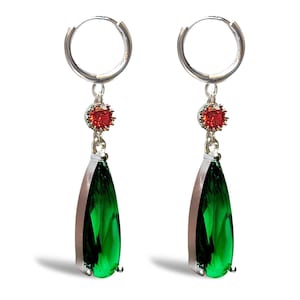 Może przedstawiać: Para srebrnych kolczyków koła z wiszącym zielonym kamieniem w kształcie łzy i małym czerwonym kamieniem akcentującym.