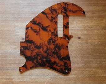 Peut inclure: Un pickguard de guitare avec un motif écaille de tortue. Le pickguard est de couleur orange chaud avec des marbrures noires. Il comporte plusieurs trous de vis et une découpe pour le micro. Fabriqué dans un matériau durable, il protège le corps de la guitare.