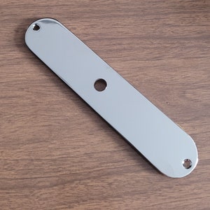 May include: A chrome-plated metal guitar control plate with two screw holes and a single hole for a knob.