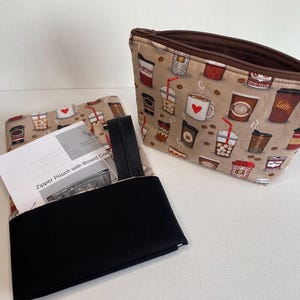 May include: Two zipper pouches with a brown background and a pattern of coffee cups. The pouch on the left is open and has a black lining. The pouch on the right is closed and has a zipper. The text "Zipper Pouch with Boxed Coffee" is printed on the pouch on the left.