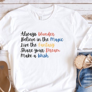 May include: White t-shirt with the text "Always Wonder Believe in the Magic Live the Fantasy Share your Dream Make a Wish" in colorful lettering.