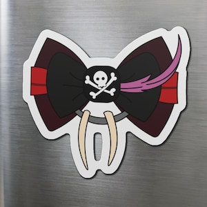 May include: A decorative magnet featuring a black bow with a skull and crossbones emblem. The bow has red and burgundy accents, with a pink feather detail. Below the bow are two ivory-coloured tusks.