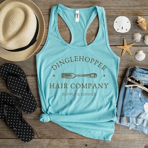 Peut inclure: Un d&eacute;bardeur bleu turquoise avec un dos nageur blanc. Le d&eacute;bardeur a un motif brun avec le texte "Dinglehopper Hair Company Supply & Service" et une image stylis&eacute;e d'une fourchette.