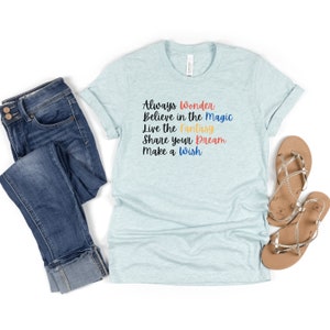 May include: A light blue t-shirt with the text "Always Wonder Believe in the Magic Live the Fantasy Share your Dream Make a Wish" printed in black with colorful accents.