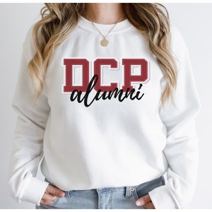 May include: White sweatshirt with a red "DCP alumni" graphic on the front.