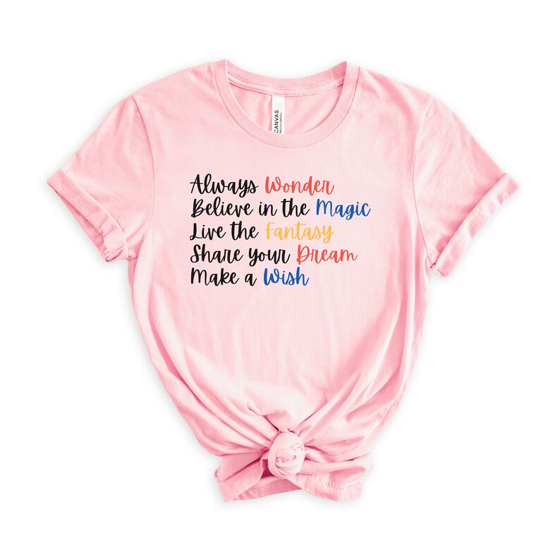 May include: Pink t-shirt with the text "Always Wonder Believe in the Magic Live the Fantasy Share your Dream Make a Wish" in colorful lettering.