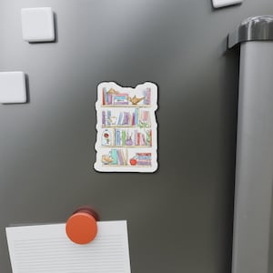 Puede incluir: Una ilustración de acuarela de una estantería llena de libros, una lámpara de genio, una rosa en una cúpula de vidrio y otros artículos decorativos.