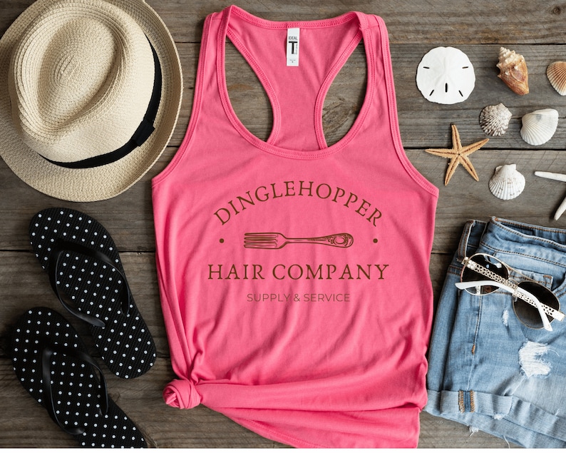 Peut inclure: Un d&eacute;bardeur rose avec un graphique brun qui dit "Dinglehopper Hair Company Supply & Service" avec un graphique de fourchette.