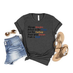 May include: A dark heather grey t-shirt with the text "Always Wonder Believe in the Magic Live the Fantasy Share your Dream Make a Wish" printed in colorful lettering.