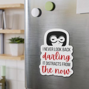 May include: White refrigerator magnet with a black and white illustration of a woman with a serious expression. The text on the magnet reads "I never look back darling it distracts from the now".