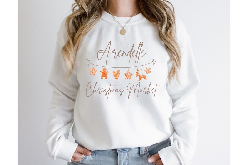 May include: White sweatshirt with a brown graphic design that says "Arendelle Christmas Market" with gingerbread cookies and stars hanging from a string.