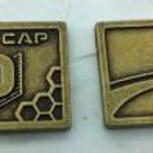 May include: Two metal tokens, one with a honeycomb pattern and the text "CAP 10 CAP", the other with a curved line and the text "10".