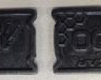 May include: Two metal tags with a textured surface. The first tag has the word "REOCCUR" in a stylized font. The second tag has a pattern of squares and the word "REOCCUR" in a stylized font.