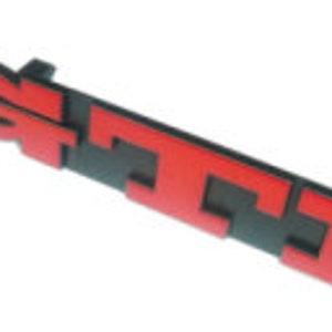 May include: Red and black GTI emblem. The emblem is a rectangular shape with the letters "GTI" in red, set against a black background. The letters are bold and stylized, with a glossy finish.