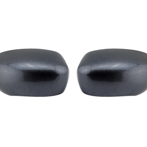 May include: A pair of automotive side mirror covers featuring a glossy black and grey carbon fiber weave pattern. These two rounded, symmetrical exterior vehicle components have a smooth, reflective finish and a curved, aerodynamic shape.