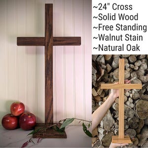 May include: A freestanding wooden cross, approximately 24 inches tall, with a walnut stain. The cross is made of solid wood and has a natural oak finish. The image also includes text that reads "~24" Cross ~Solid Wood ~Free Standing ~Walnut Stain ~Natural Oak."