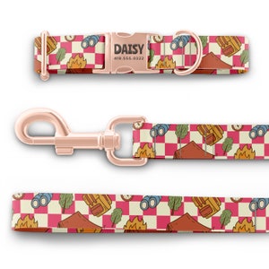 May include: A pink and white checkered dog collar and leash with a camping theme. The collar has a rose gold buckle with the name "DAISY" and phone number "419.555.0322" engraved on it.