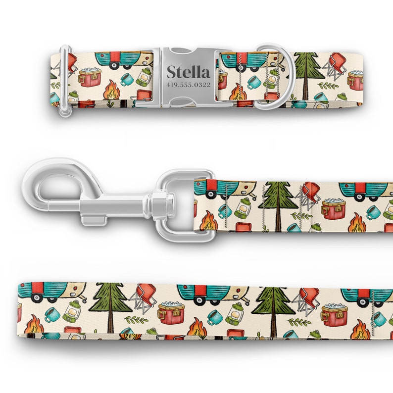 May include: A white dog collar and leash with a camping themed pattern. The pattern features a blue and red camper, a green pine tree, a red camp chair, a red cooler, a campfire, and a lantern. The collar has a silver buckle with the name "Stella" and a phone number.