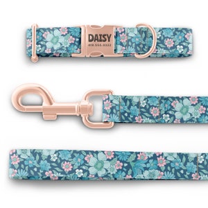 K&ouml;nnte beinhalten: Ein blaues und pinkfarbenes Blumen-Halsband und eine Leine mit ros&eacute;goldenen Beschl&auml;gen. Das Halsband hat ein personalisiertes Namensschild mit der Aufschrift "DAISY 419.555.0322".