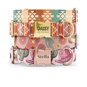 May include: Three dog collars stacked on top of each other. The top collar is brown, orange, and green with a geometric pattern. The middle collar is orange, red, and brown with a geometric pattern. The bottom collar is pink with a cactus and cowboy hat pattern. The collars have gold buckles with the names "Daisy" and "Stella" and phone numbers.