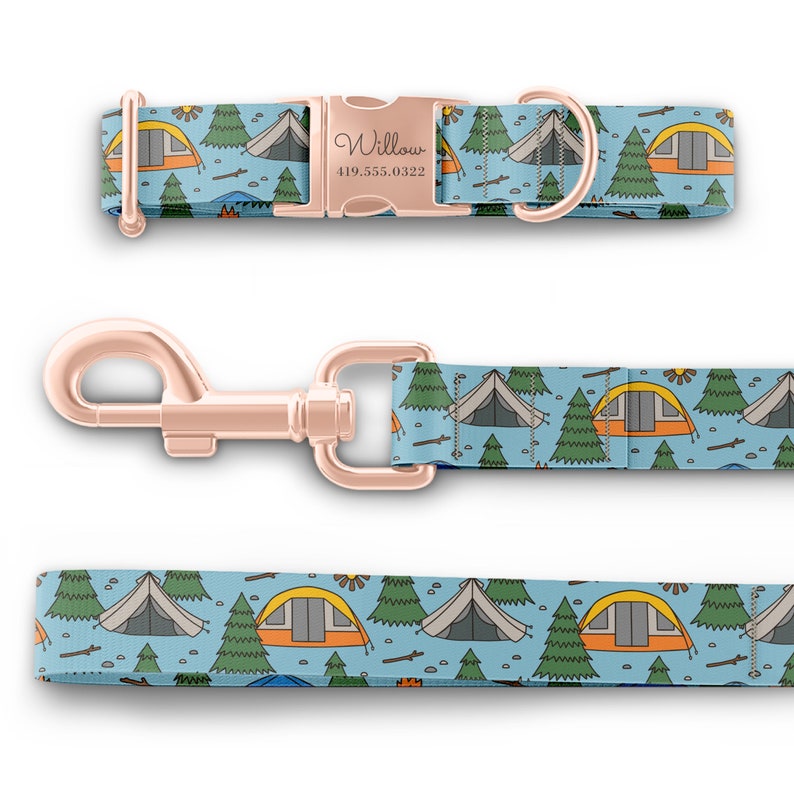 May include: A blue and green dog collar and leash set with a camping theme. The collar has a rose gold buckle with the name "Willow" and a phone number engraved on it. The leash has a rose gold clip.