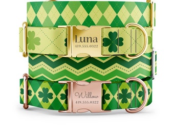 May include: Two green and gold dog collars with personalised name tags. The top collar has a gold buckle and a green shamrock pattern. The bottom collar has a rose gold buckle and a green shamrock pattern. The name tags read "Luna 419.555.0322" and "Willow 419.555.0322".