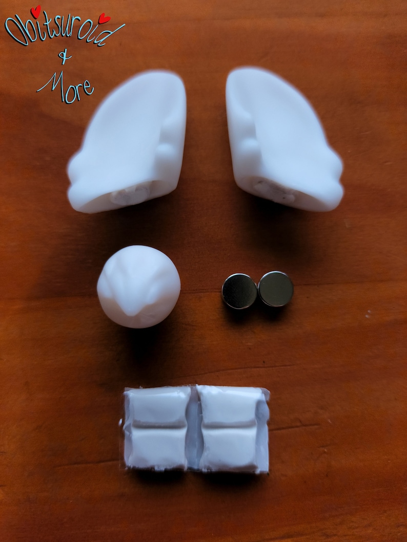 May include: A set of white plastic doll ears, a white plastic nose, two silver magnets, and two white plastic pieces with a textured surface.