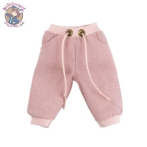 Könnte beinhalten: Rosa Jogginghose mit Kordelzug und zwei Taschen. Die Jogginghose hat einen gerippten Bund.