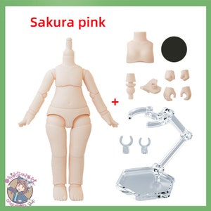 May include: A nude-colored plastic doll body with a stand. The doll is posed standing with arms outstretched. The doll is labeled "Sakura pink".