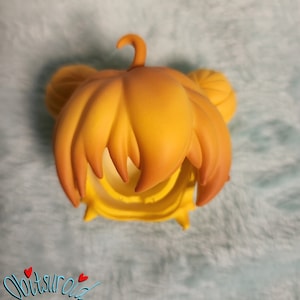 May include: A yellow doll hair wig with a high ponytail and two side buns. The wig is made of a soft, pliable material.
