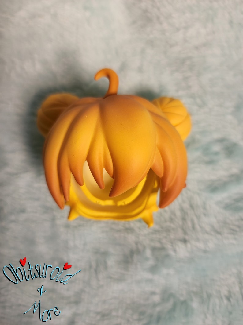 May include: A yellow doll hair wig with a high ponytail and two side buns. The wig is made of a soft, pliable material.