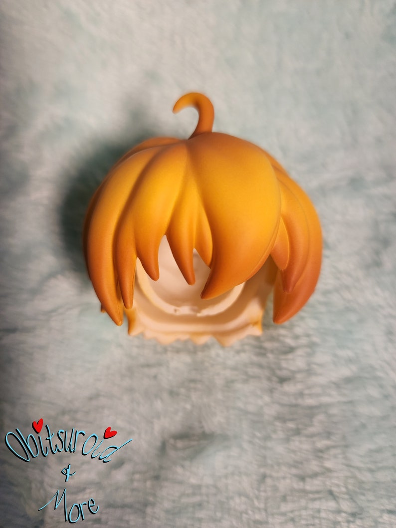 May include: A yellow-orange doll hair wig with a pumpkin shape. The wig is made of a soft, smooth material and has a natural-looking texture.