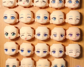 May include: A set of 25 blank doll heads with different facial expressions. The heads are made of a smooth, light-colored plastic and have painted features. The expressions include happy, sad, angry, surprised, and neutral.
