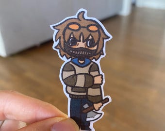 May include: A cartoon sticker of a character wearing a brown and white striped sweater, blue jeans, and a black mask with a white smile. The character is holding a brown and silver axe.
