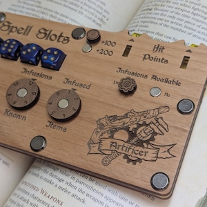 May include: Wooden tabletop gaming accessory with etched text and graphics. Features dice slots, dials, and a graphic of a gun with gears and the word "Artificer". Includes dice and magnetic components.