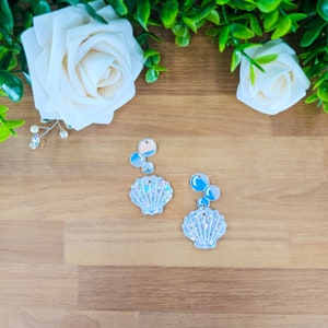 May include: A pair of iridescent white seashell earrings with blue and white iridescent bubble charms.